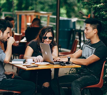 Jobseekers having coffee with laptops discussing job email alerts.